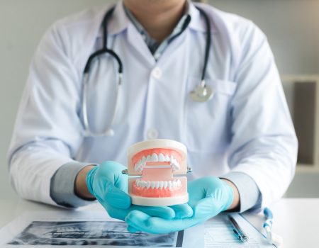 Dentist holding dentures in office room.